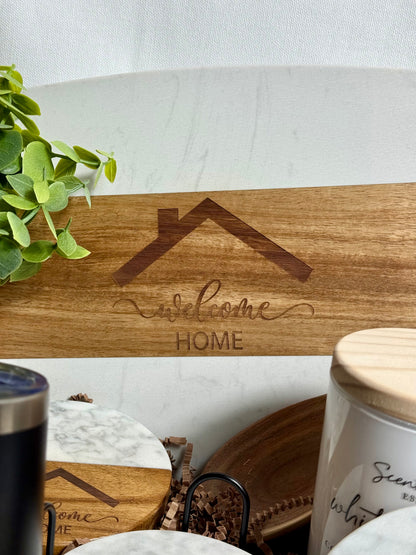 Welcome Home engraved on a white marble cutting board.